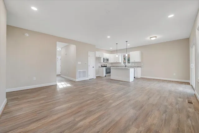 a view of an empty room with wooden floor and window