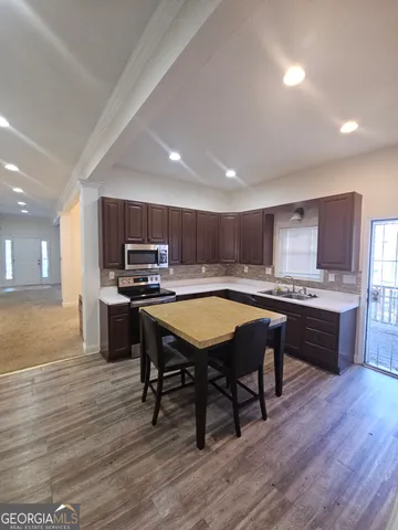 a kitchen with kitchen island granite countertop wooden floors stainless steel appliances and a sink