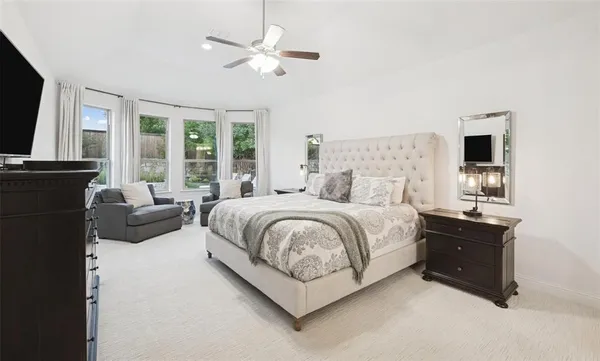 a spacious bedroom with a bed a couch and a flat tv screen