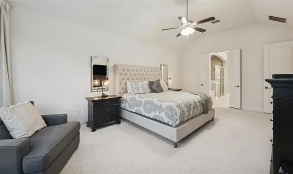 a bedroom with a large bed couch and a ceiling fan