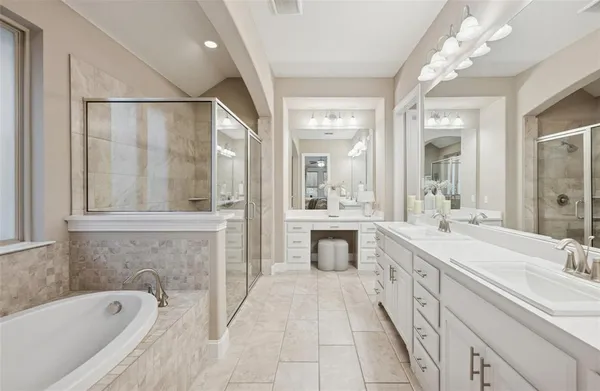 a spacious bathroom with a tub sink shower and mirror