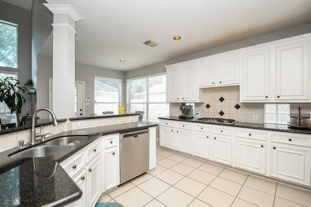 a kitchen with granite countertop white cabinets white appliances with a sink and dishwasher