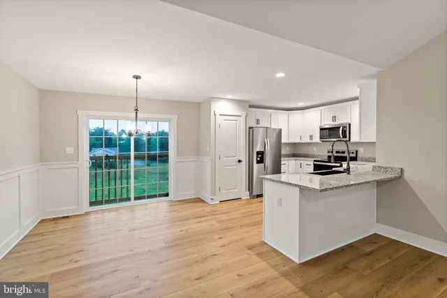 a kitchen with stainless steel appliances granite countertop a refrigerator a stove a sink and a wooden floors