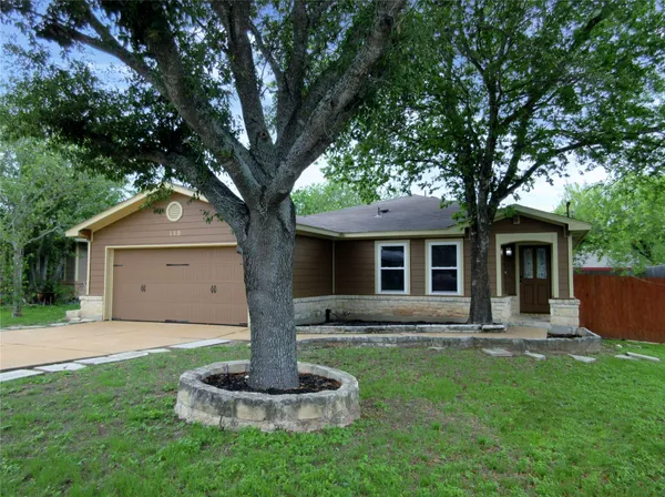 a front view of house with a garden and trees