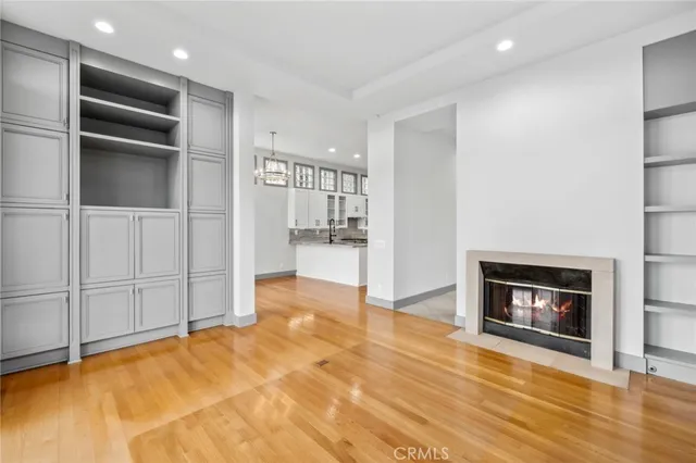 a view of an empty room and kitchen with furniture wooden floor and window