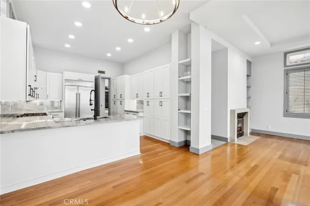 a view of a kitchen with kitchen island a sink wooden floor and stainless steel appliances