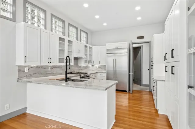 a kitchen with stainless steel appliances granite countertop a refrigerator a sink and white cabinets