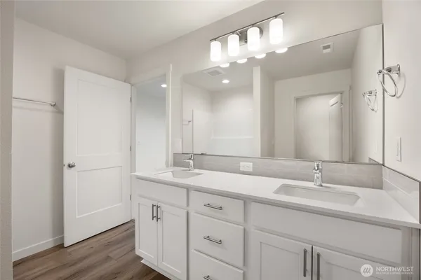 a view of a hallway with wooden floor and a bathroom