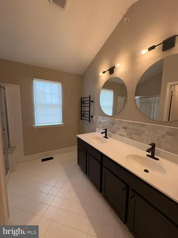 a bathroom with a double vanity sink mirror and bathtub