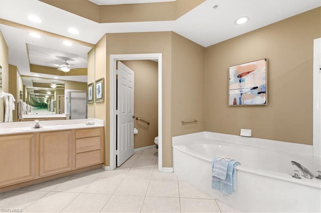 2090 Aberdeen Lane, Unit 101 Naples, FL 34109 - Photo 12 of 42 a spacious bathroom with a tub sink and mirror