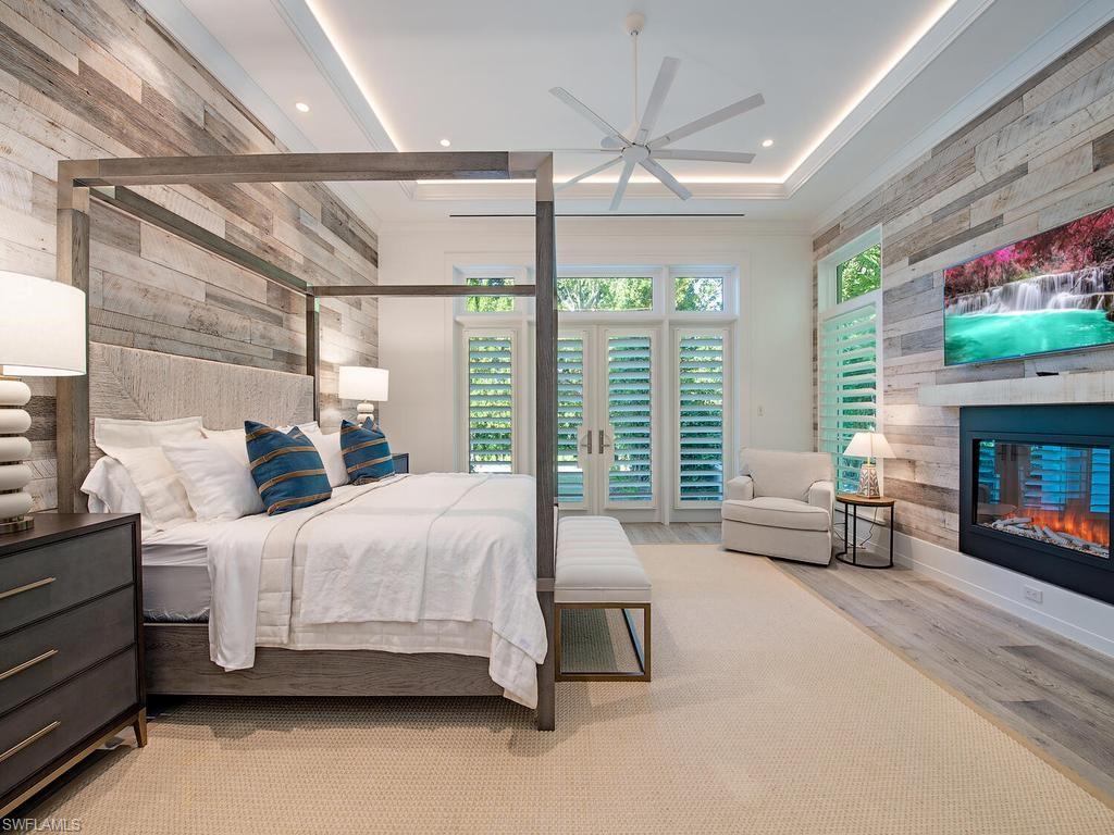 225 4th Avenue North Naples, FL 34102 - Photo 12 of 42 a bedroom with a bed a flat screen tv and a fireplace