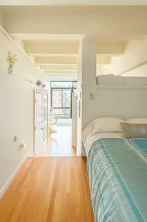 a spacious bedroom with a bed and wooden floor