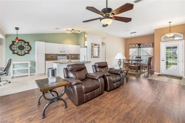 a living room with furniture kitchen view and a wooden floor