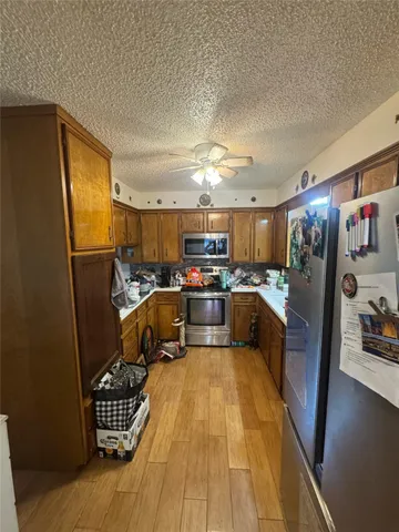 a kitchen with stainless steel appliances granite countertop a refrigerator a sink a stove and a wooden floors