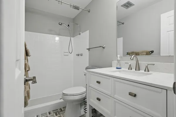 a bathroom with a granite countertop sink mirror vanity and toilet