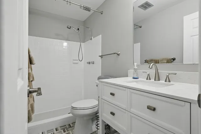 a bathroom with a granite countertop sink mirror vanity and toilet