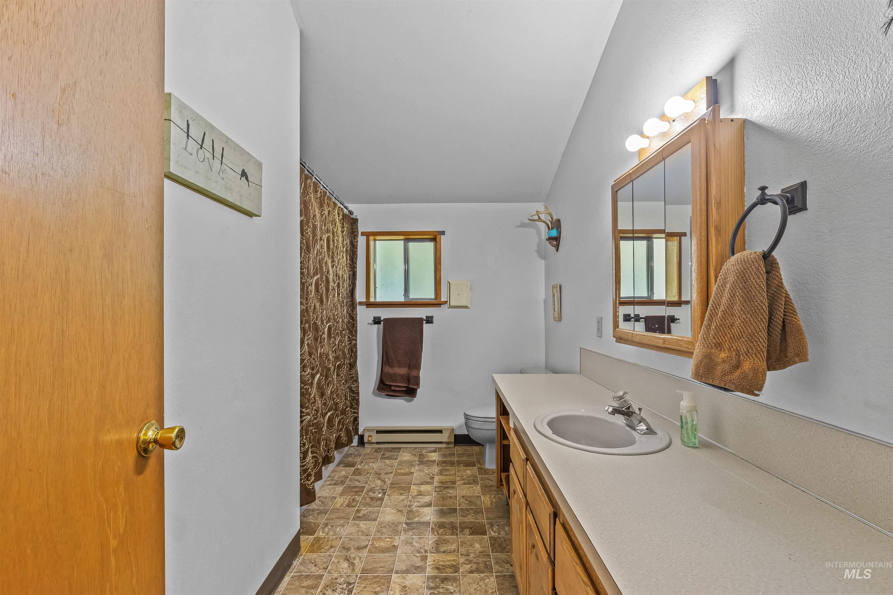 302 Berger Street Riggins, ID 83549 - Photo 11 of 47 Bathroom with a baseboard radiator, vanity, stone finish floors, and a shower with curtain
