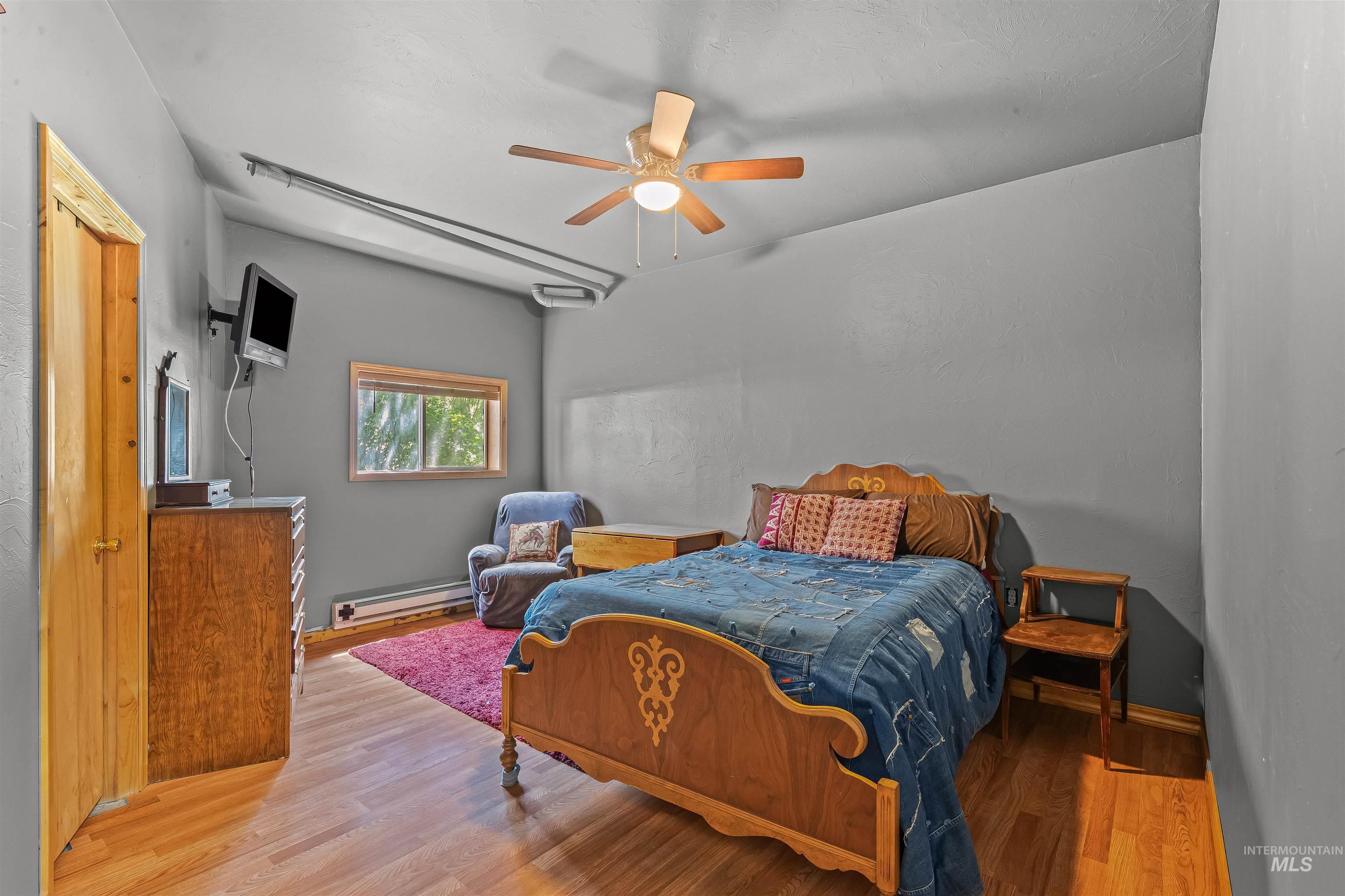 302 Berger Street Riggins, ID 83549 - Photo 16 of 47 Bedroom with wood finished floors, a baseboard radiator, and ceiling fan