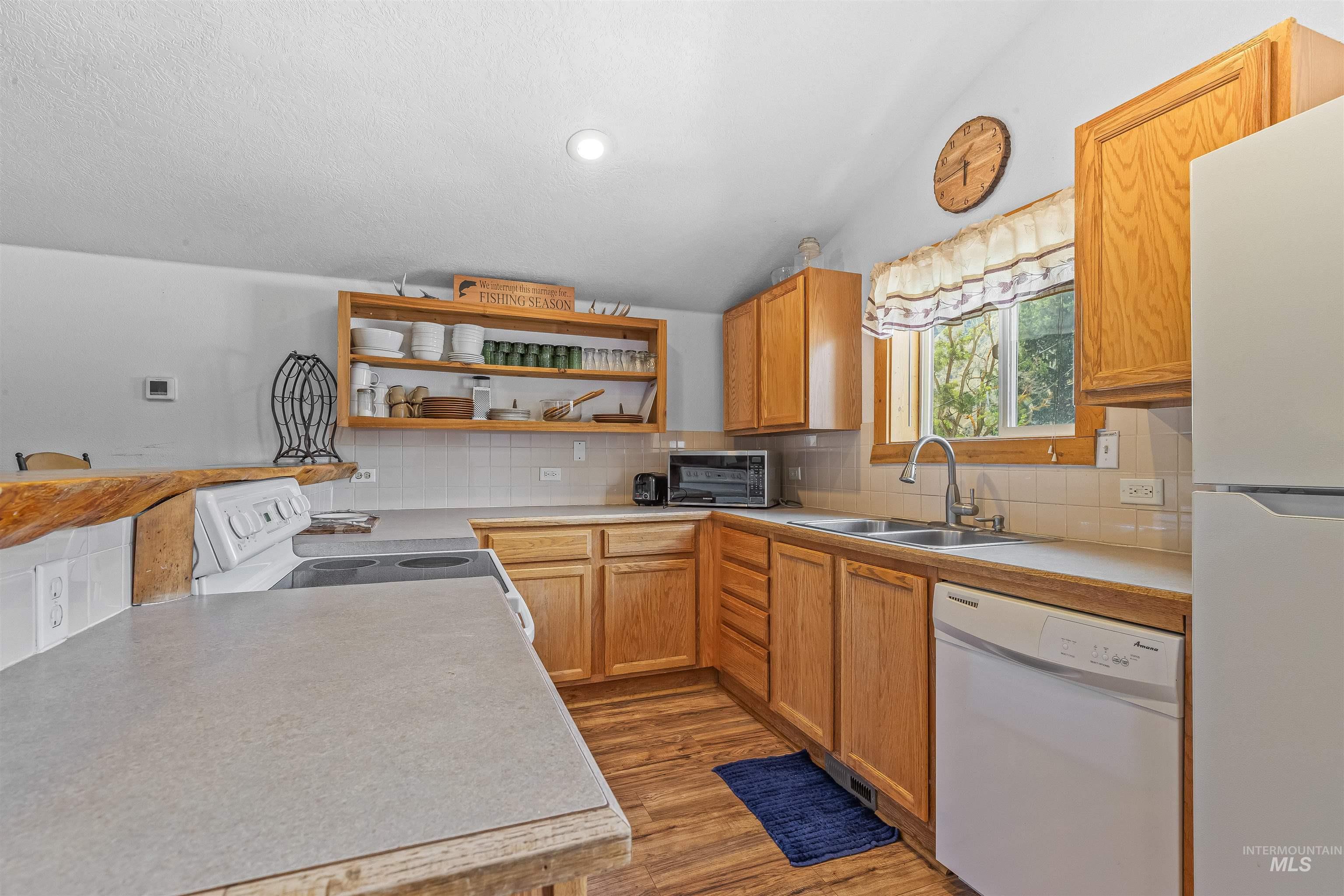 302 Berger Street Riggins, ID 83549 - Photo 23 of 47 Kitchen with white appliances, open shelves, light wood-style flooring, decorative backsplash, and light countertops