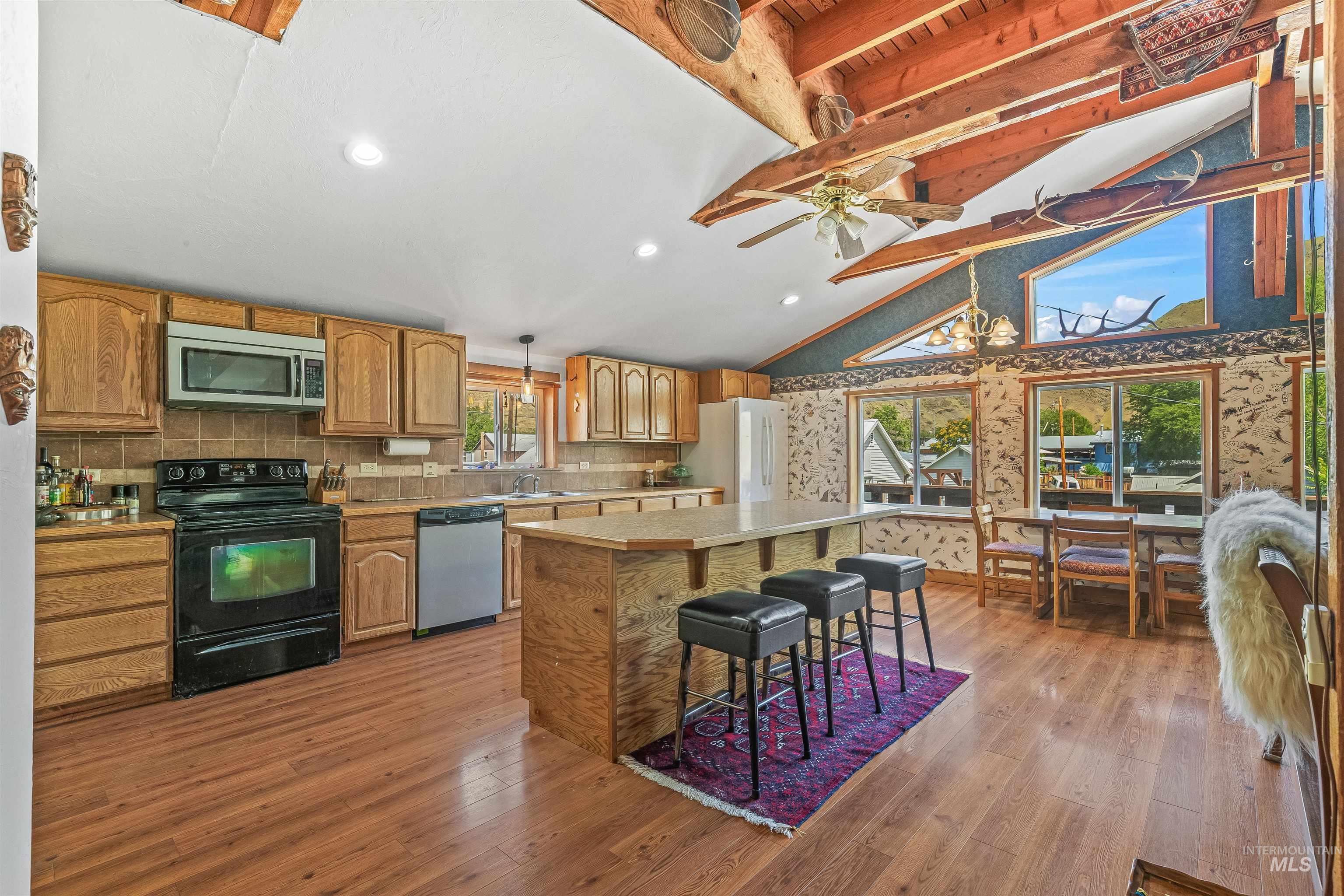 302 Berger Street Riggins, ID 83549 - Photo 6 of 47 Kitchen with appliances with stainless steel finishes, light countertops, a kitchen island, light wood-style flooring, and beamed ceiling