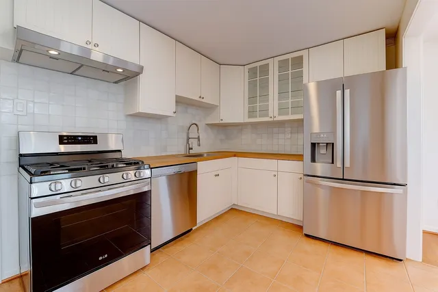 a kitchen with stainless steel appliances granite countertop a sink and a white cabinets