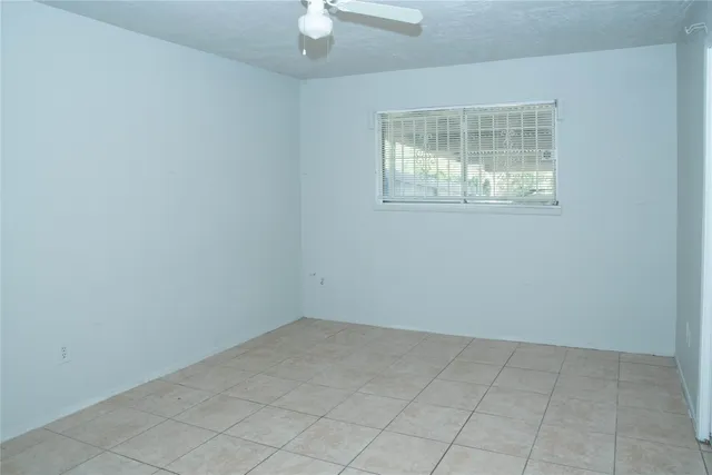 an empty room with wooden floor chandelier fan and windows