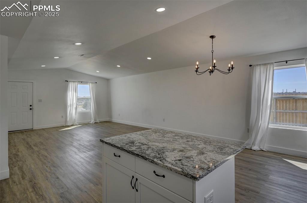 1436 Brewery Road Pueblo, CO 81001 - Photo 11 of 40 Kitchen with a chandelier, light stone countertops, wood finished floors, white cabinetry, and vaulted ceiling