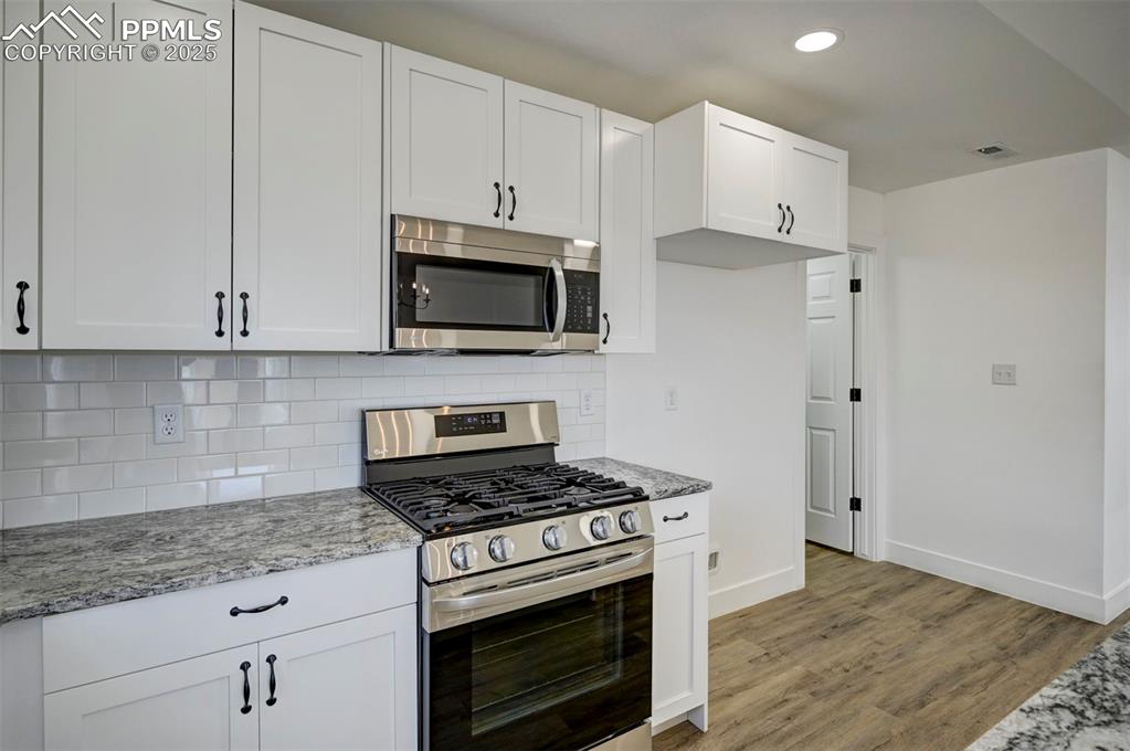 1436 Brewery Road Pueblo, CO 81001 - Photo 13 of 40 Kitchen featuring light wood-type flooring, stainless steel appliances, light stone counters, and visible vents