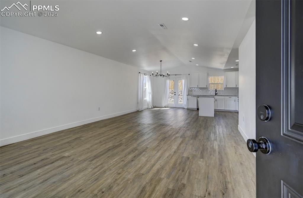 1436 Brewery Road Pueblo, CO 81001 - Photo 3 of 40 Unfurnished living room with baseboards, lofted ceiling, wood finished floors, and a chandelier