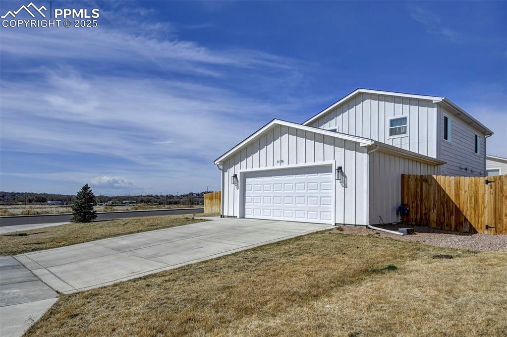 1436 Brewery Road Pueblo, CO 81001 - Photo 38 of 40 View of property exterior featuring board and batten siding, driveway, fence, and an attached garage