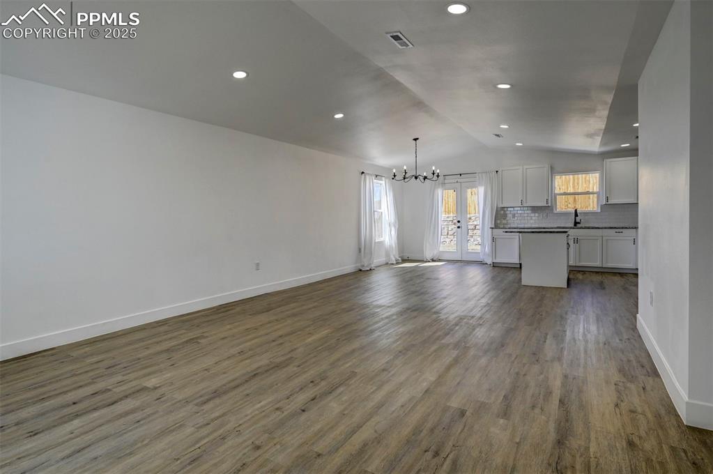 1436 Brewery Road Pueblo, CO 81001 - Photo 5 of 40 Unfurnished living room featuring dark wood-style floors, lofted ceiling, baseboards, visible vents, and an inviting chandelier