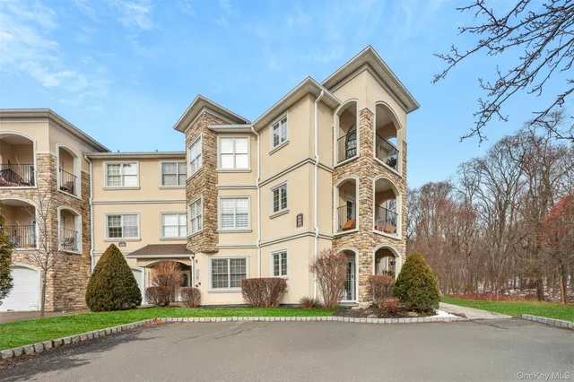 a front view of a residential apartment building with yard and parking