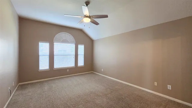 an empty room with a chandelier fan and windows
