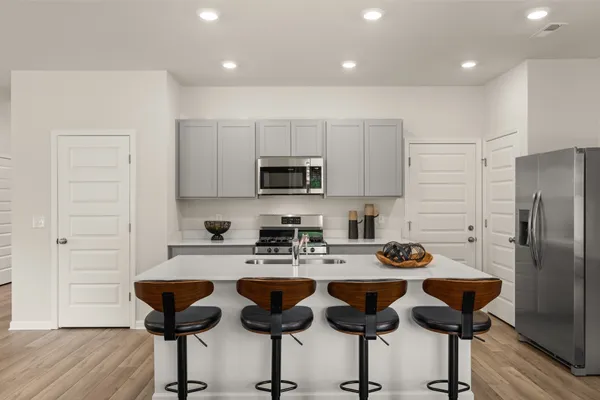 a room with stainless steel appliances kitchen island granite countertop a stove and a sink