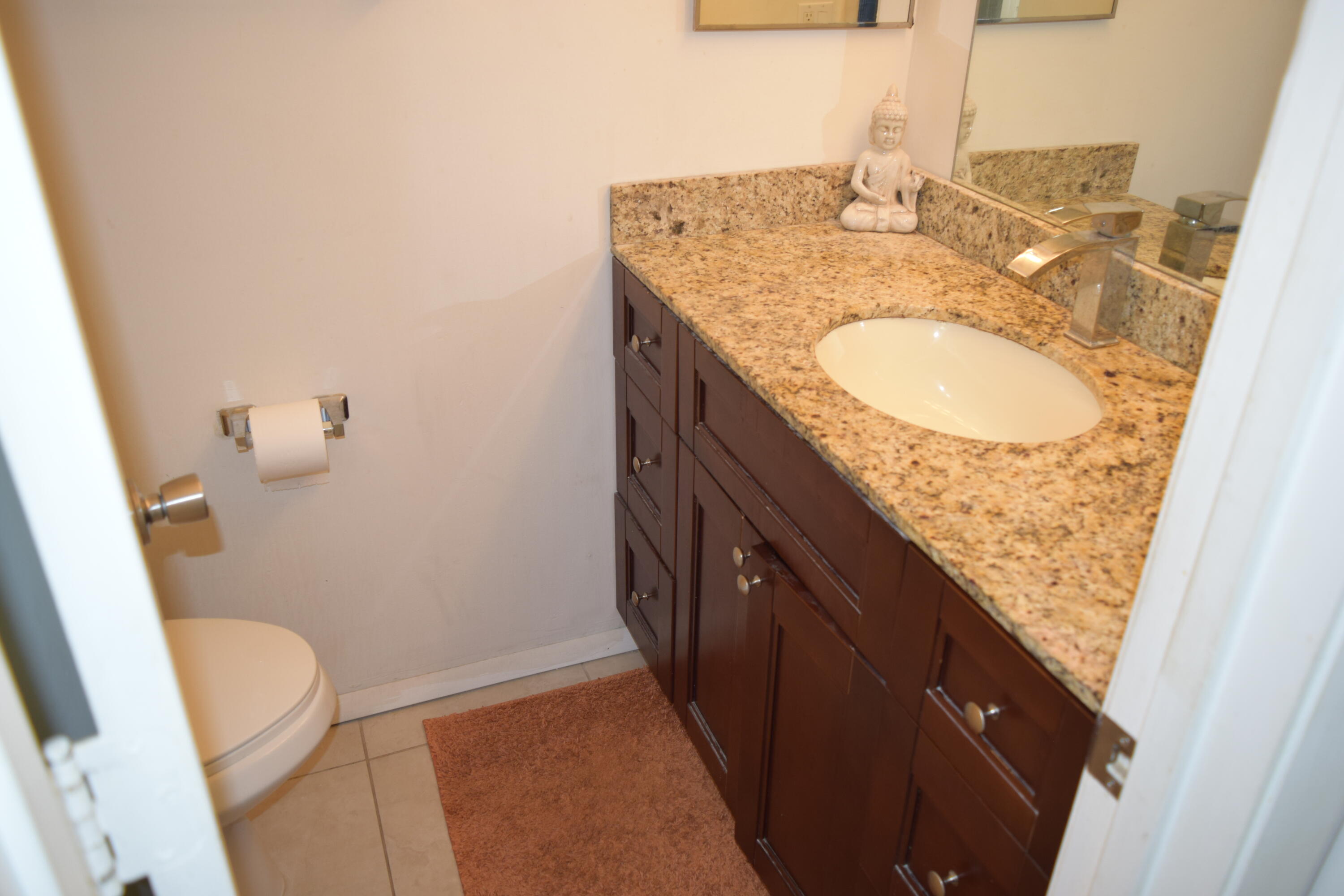 4988 Sable Pine Circle, Unit A2 West Palm Beach, FL 33417 - Photo 17 of 32 a bathroom with a granite countertop sink and a mirror