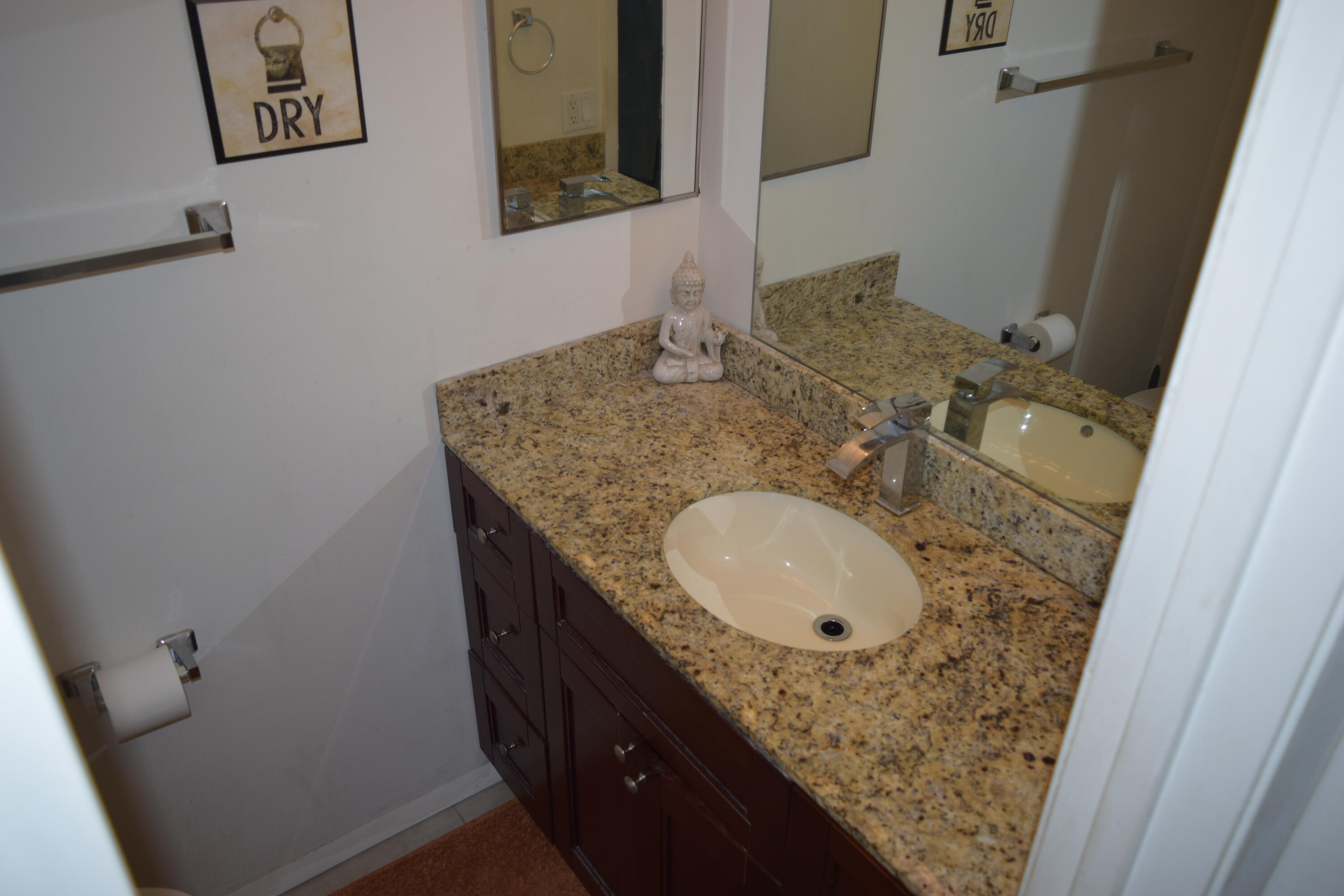 4988 Sable Pine Circle, Unit A2 West Palm Beach, FL 33417 - Photo 18 of 32 a bathroom with a granite countertop sink a mirror and vanity