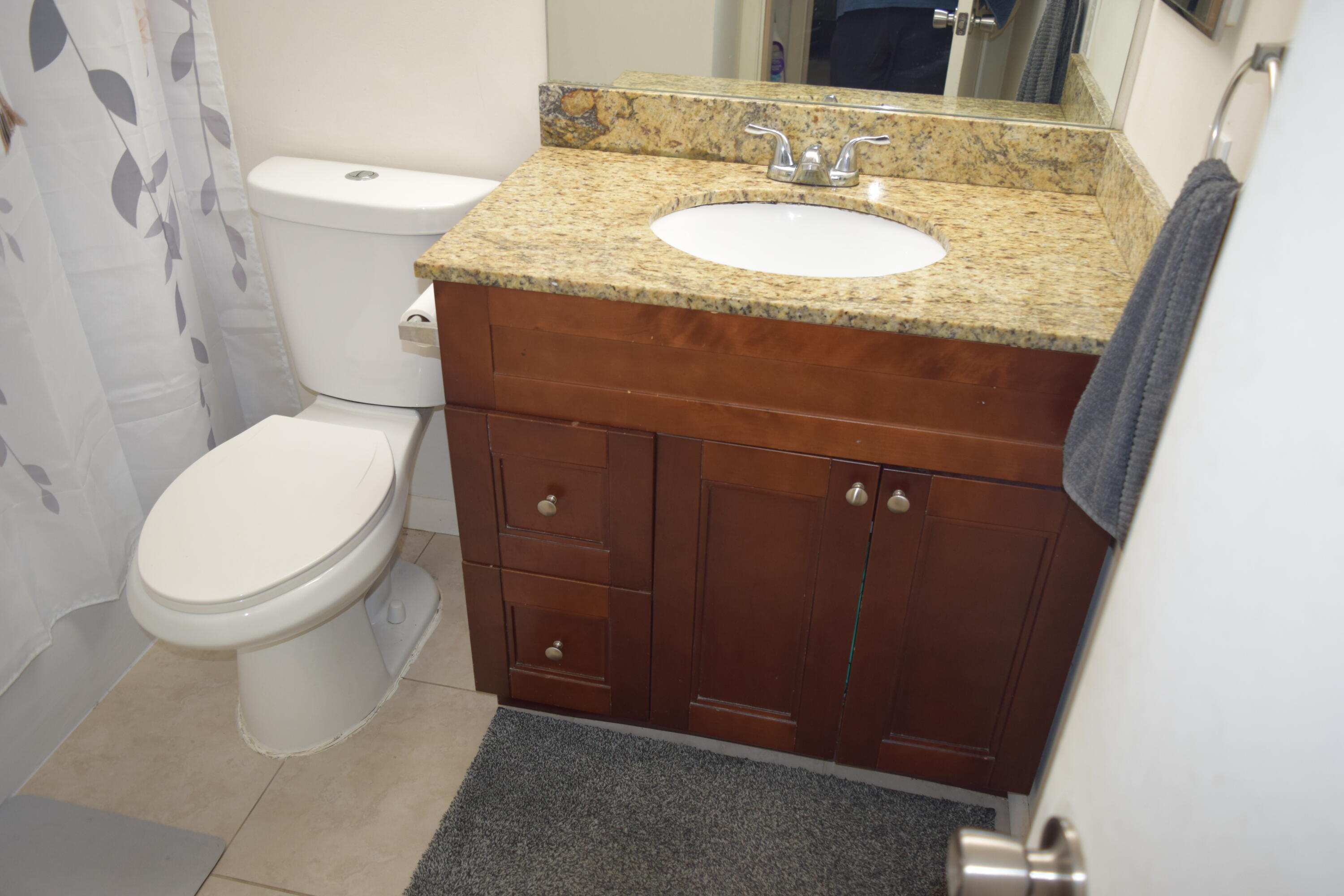 4988 Sable Pine Circle, Unit A2 West Palm Beach, FL 33417 - Photo 20 of 32 a bathroom with a granite countertop toilet and a sink