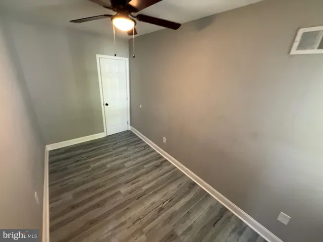 an empty room with wooden floor and fan