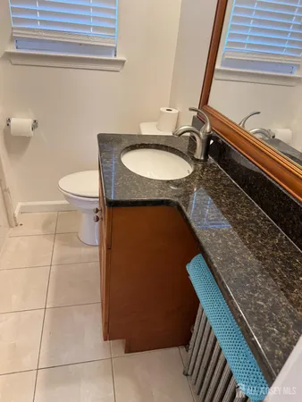 a bathroom with a granite countertop sink and a toilet