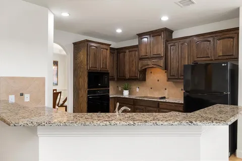 a kitchen with granite countertop wooden cabinets and refrigerator