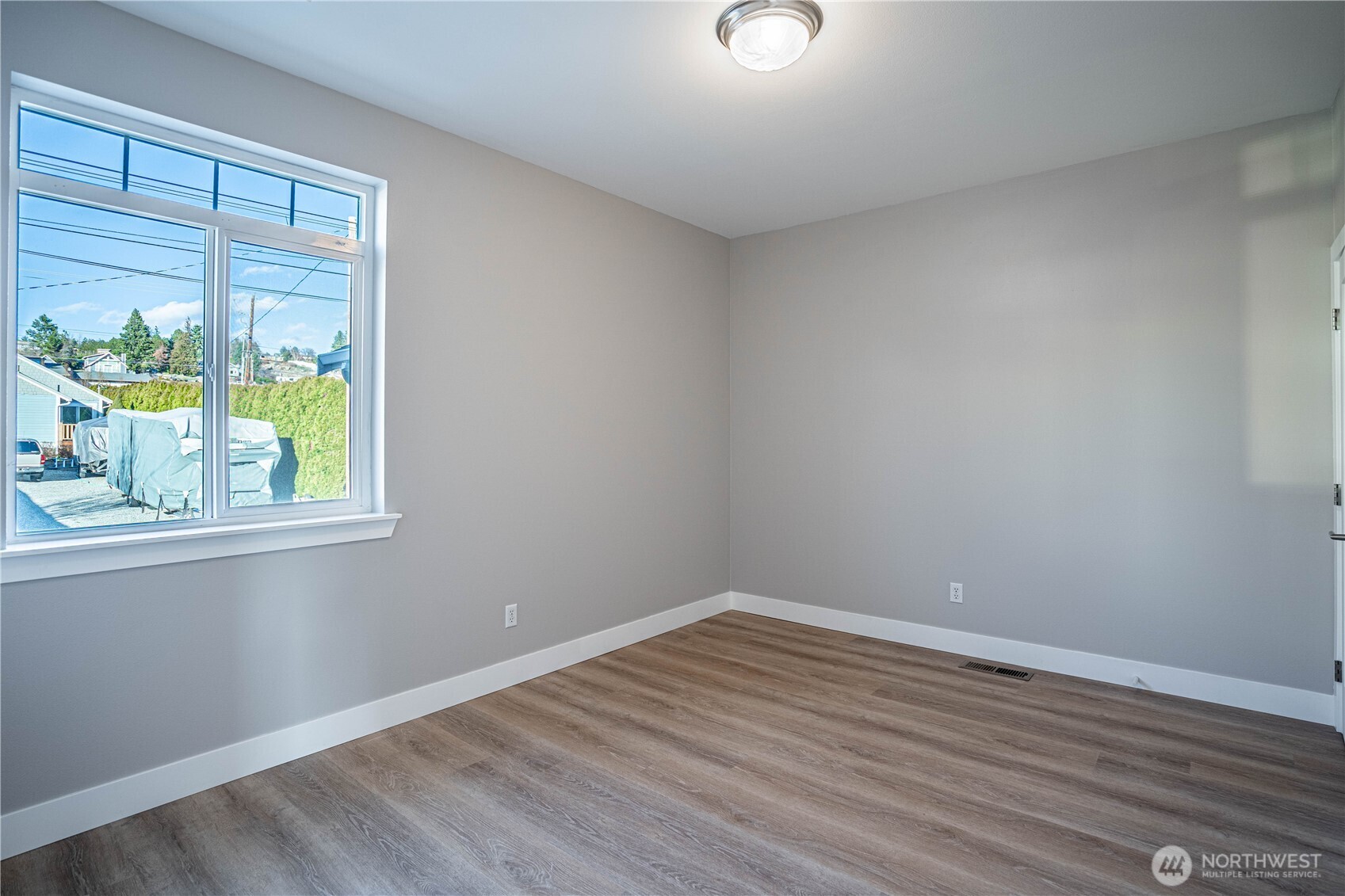744 Wapato Way, Unit B Manson, WA 98831 - Photo 13 of 32 a view of an empty room with wooden floor and a window