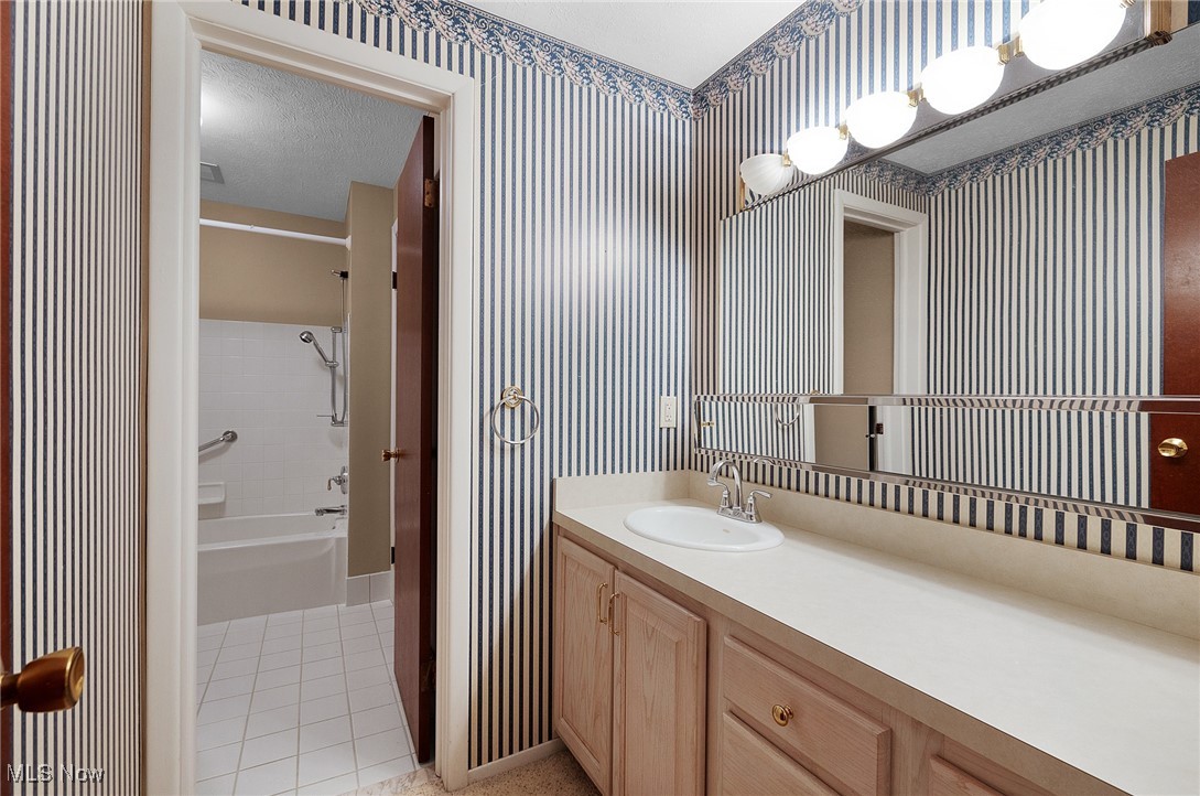 6474 State Road, Unit I10 Parma, OH 44134 - Photo 19 of 31 Full bathroom with wallpapered walls, light tile patterned floors, washtub / shower combination, and vanity