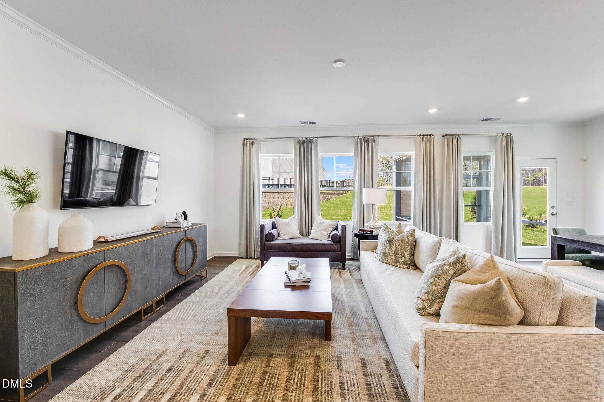 1004 Red Finch Way Angier, NC 27501 - Photo 10 of 42 a living room with furniture a flat screen tv and a floor to ceiling window