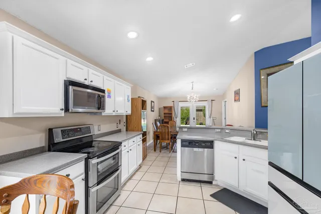 a kitchen with stainless steel appliances granite countertop a stove top oven a sink dishwasher a refrigerator and a dining table with wooden floor