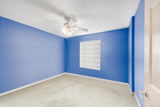 an empty room with windows and ceiling fan