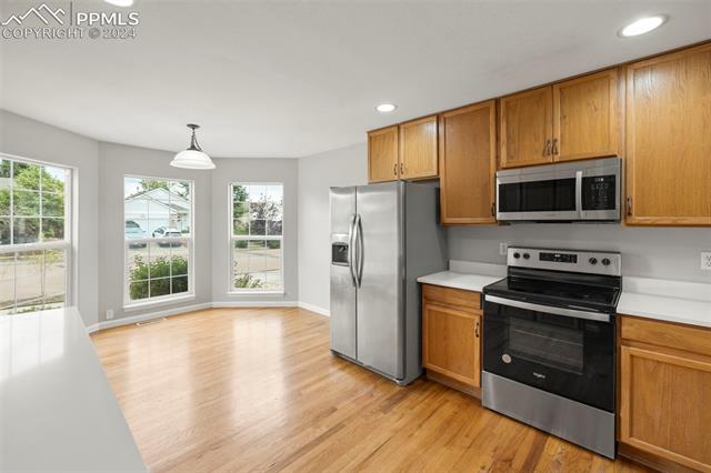 6725 Akron Road Colorado Springs, CO 80923 - Photo 8 of 50 Kitchen with appliances with stainless steel finishes, pendant lighting, and light hardwood / wood-style floors