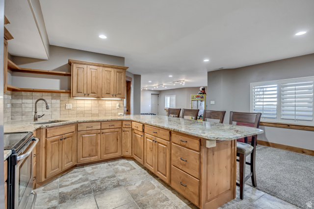 896 West 675 South Mapleton, UT 84664 - Photo 48 of 77 Kitchen with a kitchen breakfast bar, light stone countertops, electric range, tasteful backsplash, and open shelves