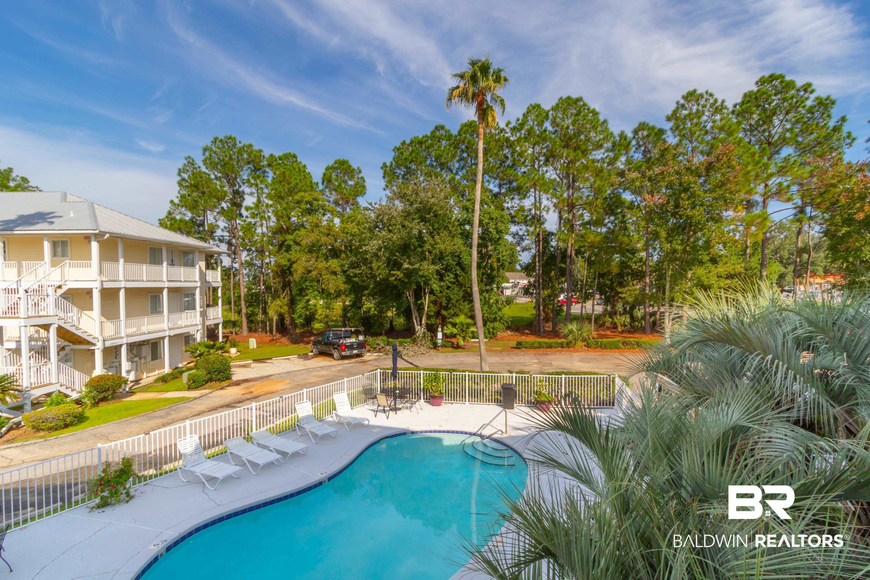 25957 Canal Road, Unit 208 Orange Beach, AL 36561 - Photo 13 of 28 Outdoor swimming pool with integrated steps, surrounded by a white deck and white perimeter fencing