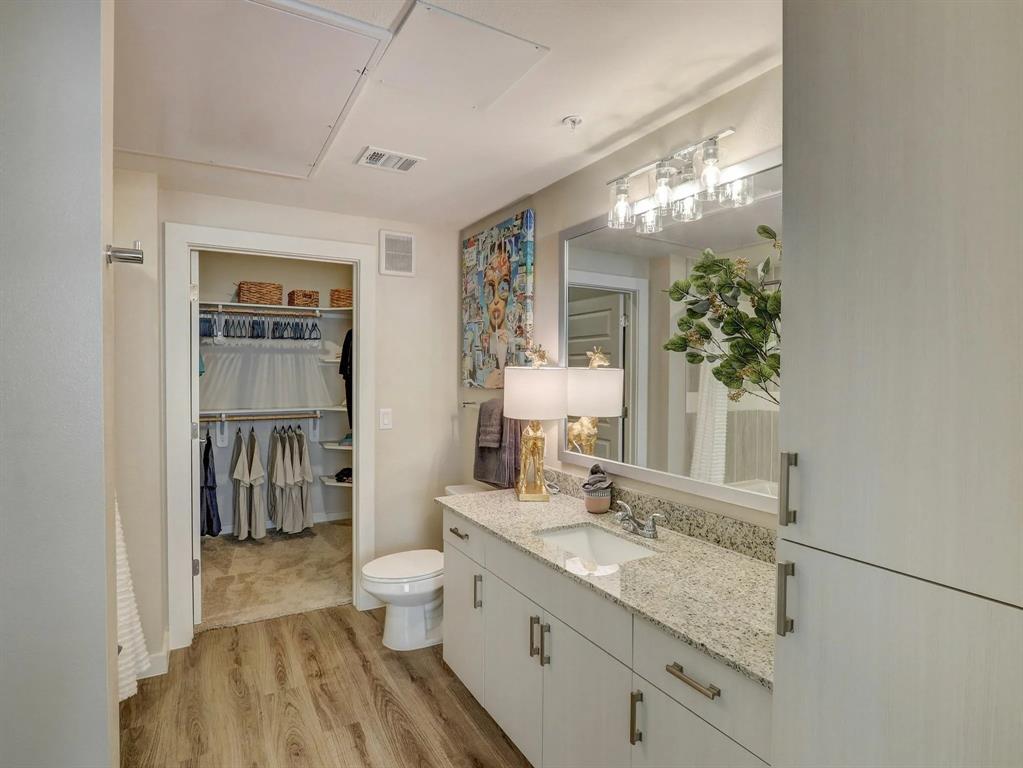 a spacious bathroom with a granite countertop sink a toilet a shower and a mirror