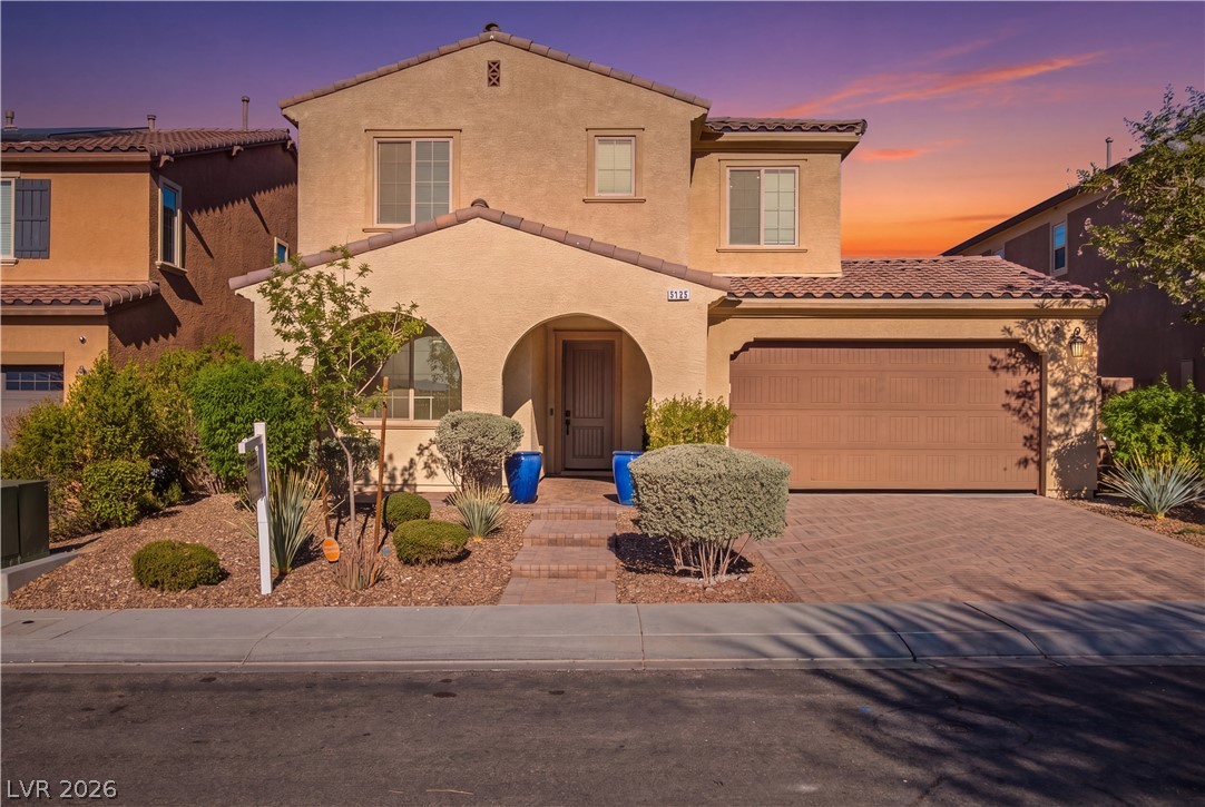 2182 Trivero Street Henderson, NV 89044 - Photo 4 of 50 A classic two-story stucco exterior stands behind a paved driveway and low-maintenance desert landscaping.